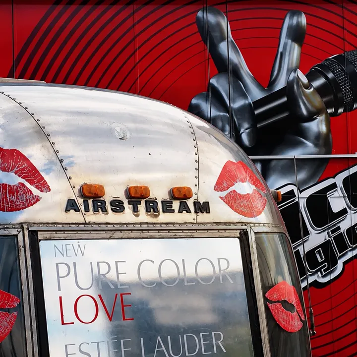 Arrière d'une caravane Airstream habillée Estée Lauder Pure Color Love, couverte de bouches rouges, micro The Voice au-dessus