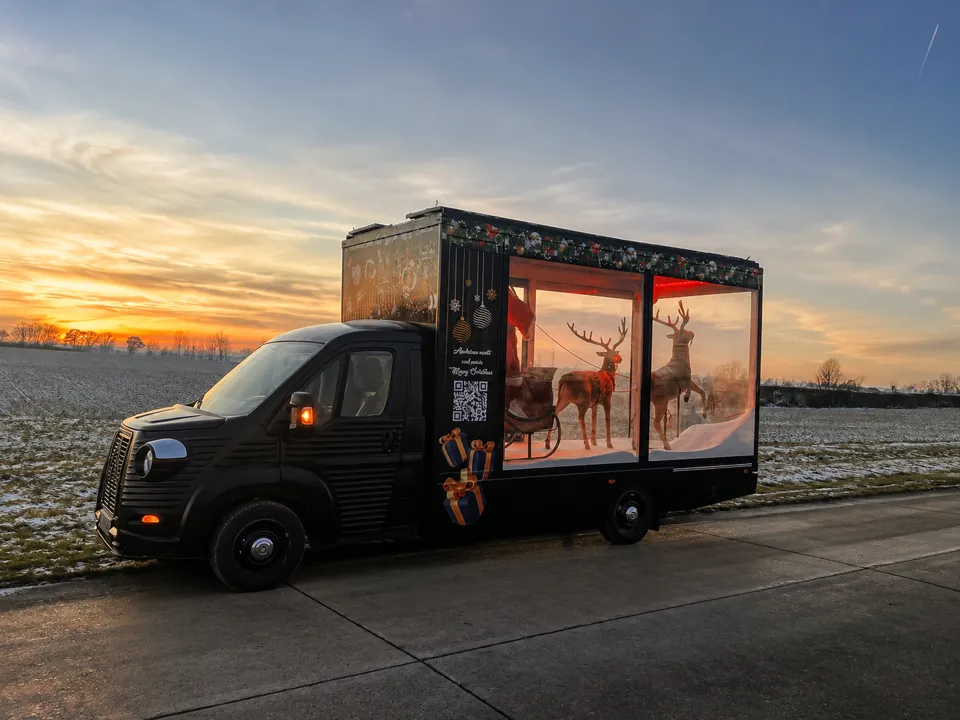 Citroën HY noir à vitrine de Noël, rennes en vitrine, au coucher du soleil sur une route de campagne